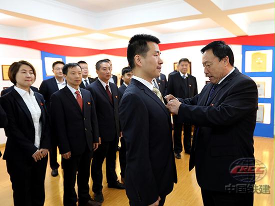 10月18日上午8时,在收看党的十九大开幕会前,中国铁建二十局四公司机关党委组织开展了“党魂传承寄初心,牢记誓词奋勇行”主题党建活动,公司党委书记秦浩贤为青年党员佩戴党徽,并带领大家重温入党誓词,有效增强了组织凝聚力和战斗力,进一步坚定了发展信心。图为:公司党委书记秦浩贤为青年党员佩戴党徽(黎青川 摄).jpg