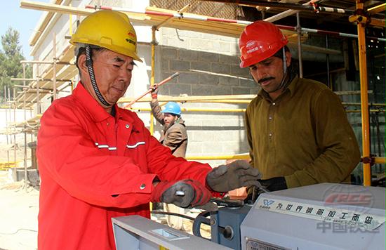 在援阿富汗国家职业技术学院建设工地,中国工人正向阿工人传授采用无污染钢筋加工制作技术 张记力 摄影.jpg